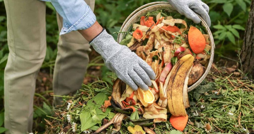 Persona con guantes echando en la huerta compost casero