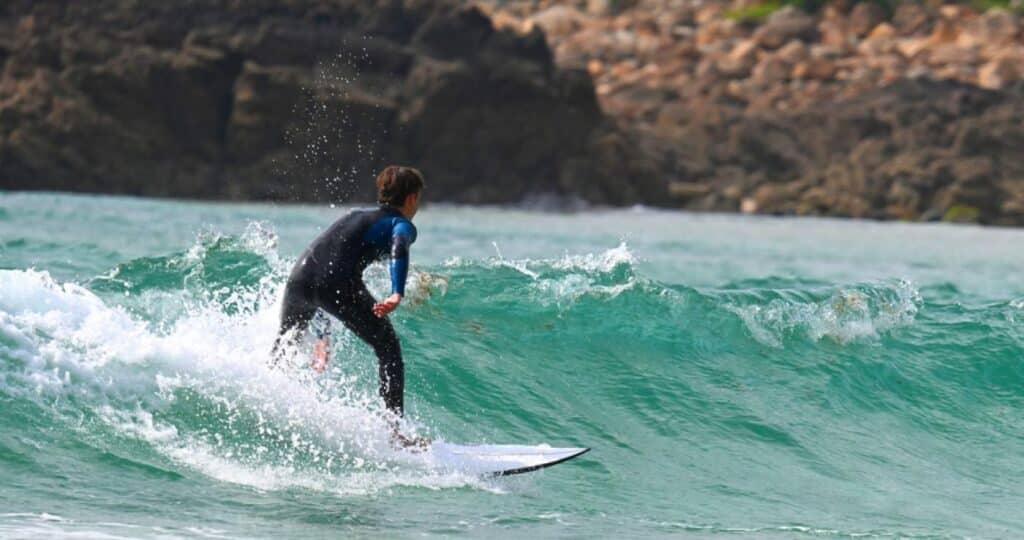 Persona de espaldas surfeando en la Playa de Doniños