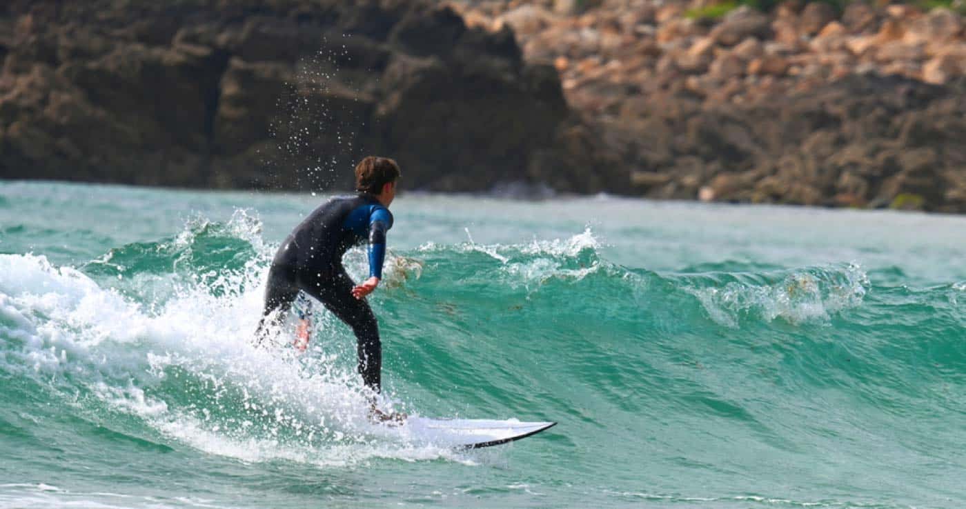 Persona de espaldas surfeando en la Playa de Doniños